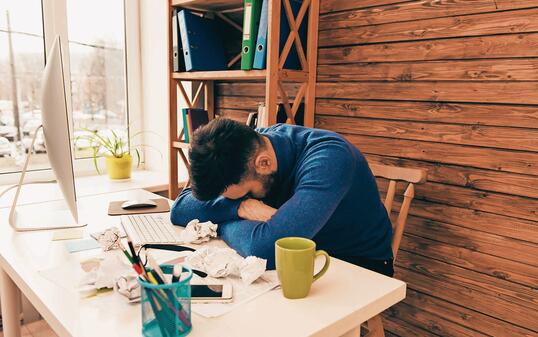 Exhausted businessman sleeping on table after hard working day