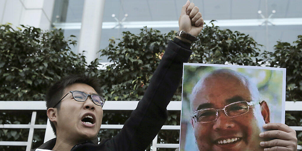 Aktivist in Hongkong mit den Konterfeis der chinesischen Dissidenten Qin Yongmin (l) und Wu Gan