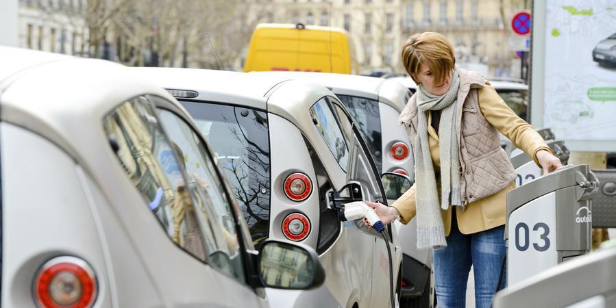 Woman charging Electric Car on Paris Street Woman charging Electric Car on Paris Street