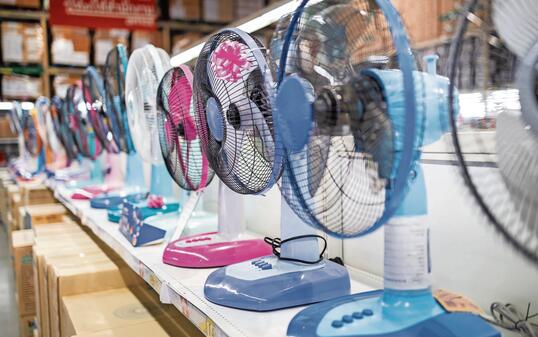 Fan for cooling in an electronics shop,various brands of electrical fans display on a shelf at supermarket in sunny hot summer day,choosing to buy energy efficient appliances,save energy concept