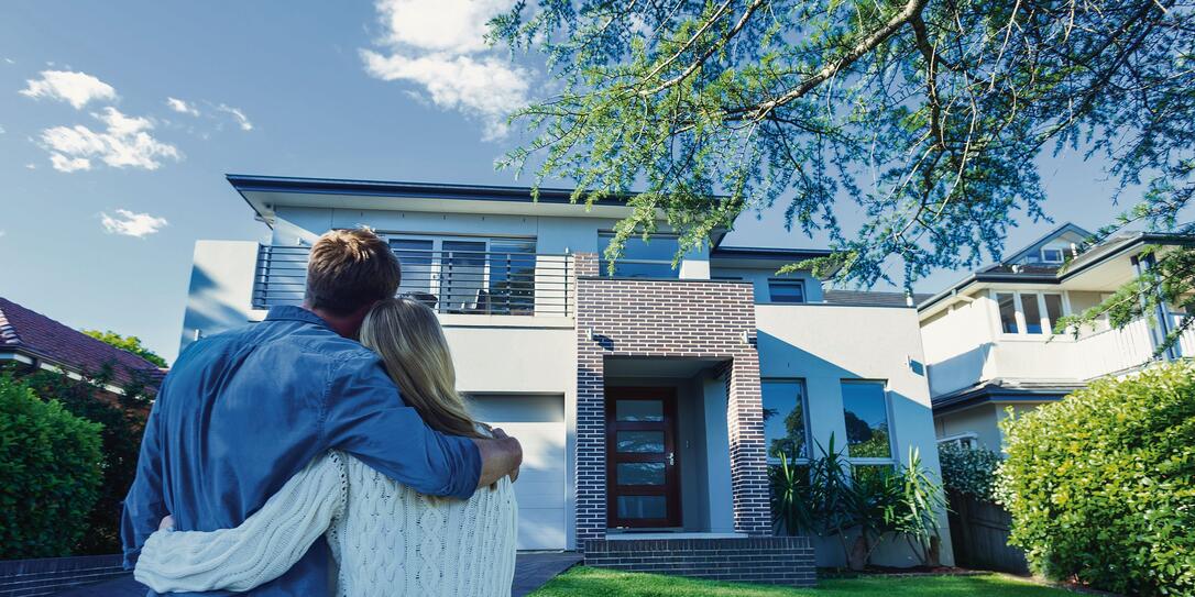 Couple standing in front of their new home.