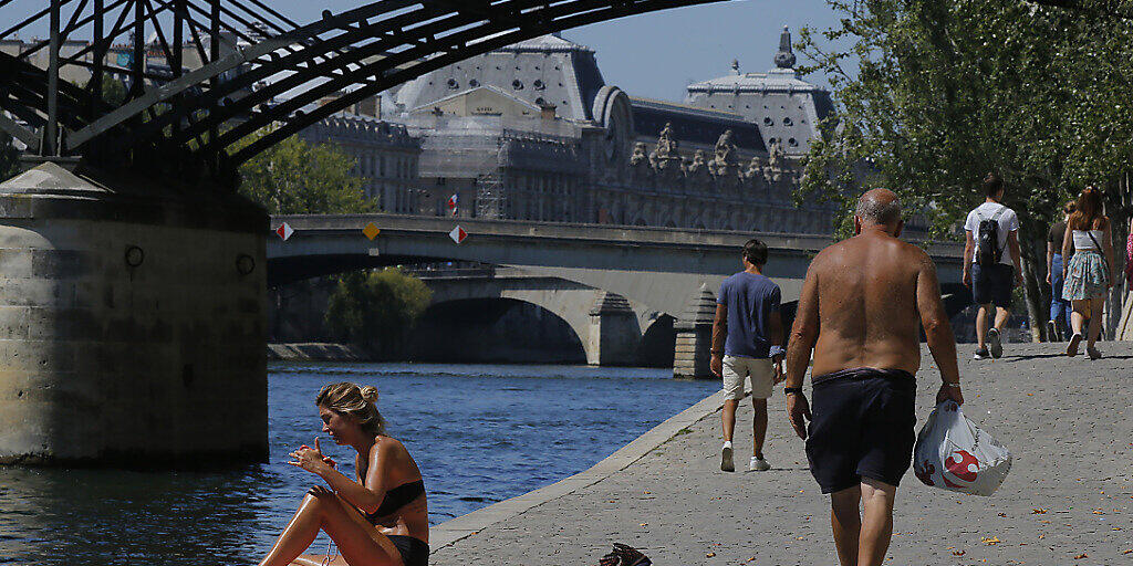 Menschen genießen das sonnige Wetter am Pariser Seineufer. Im Kampf gegen das Coronavirus gilt nun auch in Paris eine Maskenpflicht an zahlreichen öffentlichen Orten im Freien. Foto: Michel Euler/AP/dpa