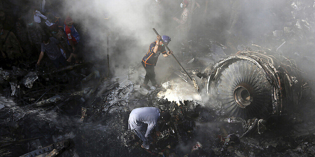 ARCHIV - Freiwillige Helfer und Einsatzkräfte suchen nach dem Absturz einer Maschine der Fluggesellschaft Pakistan International Airlines nach Überlebenden. Foto: Fareed Khan/AP/dpa