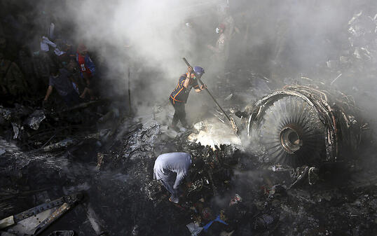 ARCHIV - Freiwillige Helfer und Einsatzkräfte suchen nach dem Absturz einer Maschine der Fluggesellschaft Pakistan International Airlines nach Überlebenden. Foto: Fareed Khan/AP/dpa