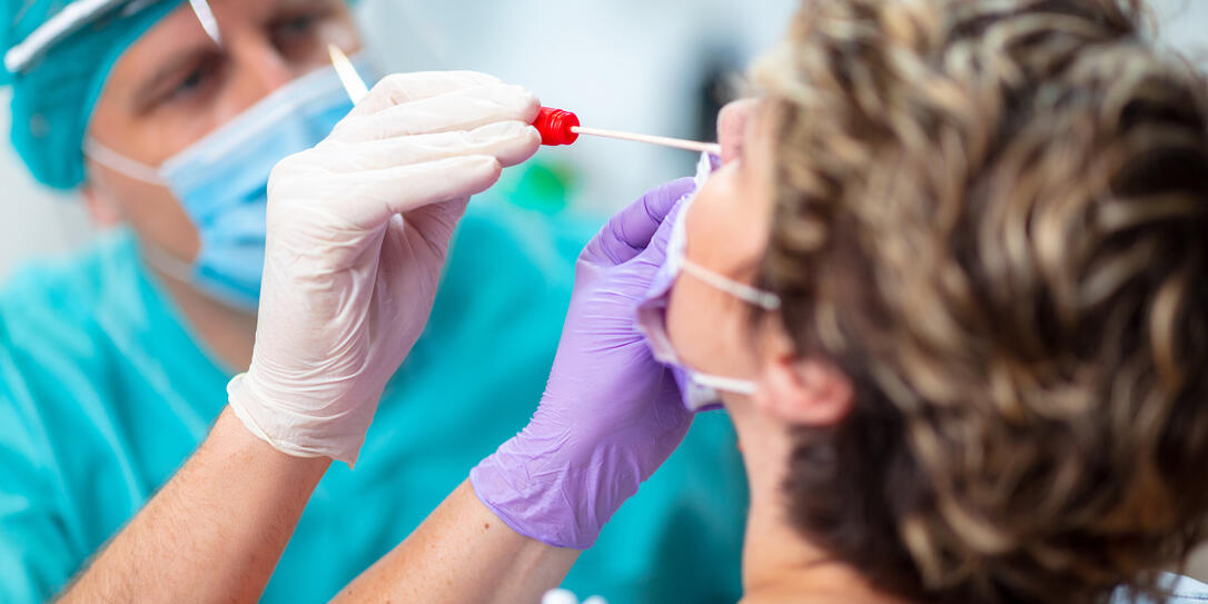 Doctor wearing surgical gloves taking nasal swab from female patient Doctor wearing surgical gloves taking nasal swab from female patient