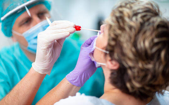 Doctor wearing surgical gloves taking nasal swab from female patient