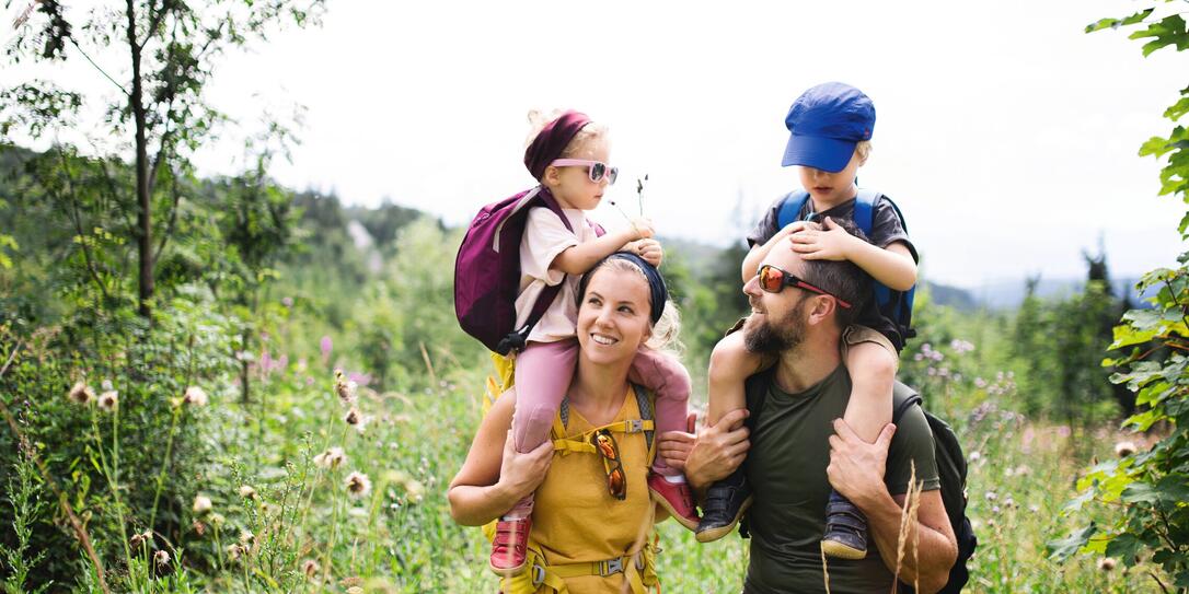Family with small children hiking outdoors in summer nature.