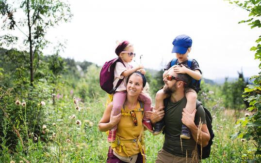 Family with small children hiking outdoors in summer nature.