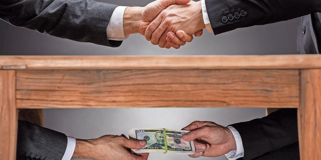 Businesspeople Shaking Hands And Taking Bribe Under Table