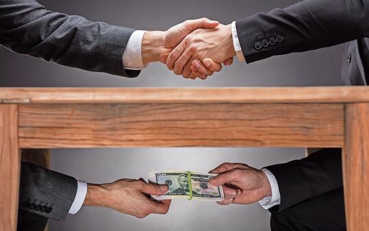 Businesspeople Shaking Hands And Taking Bribe Under Table
