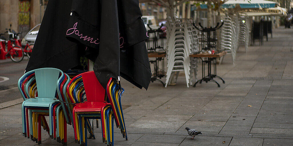 Stühle und Tische stapeln sich auf einer Bar-Terrasse in Barcelona. Foto: Emilio Morenatti/AP/dpa
