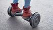 Close up of woman using hoverboard on asphalt road. Feet on electrical scooter outdoor