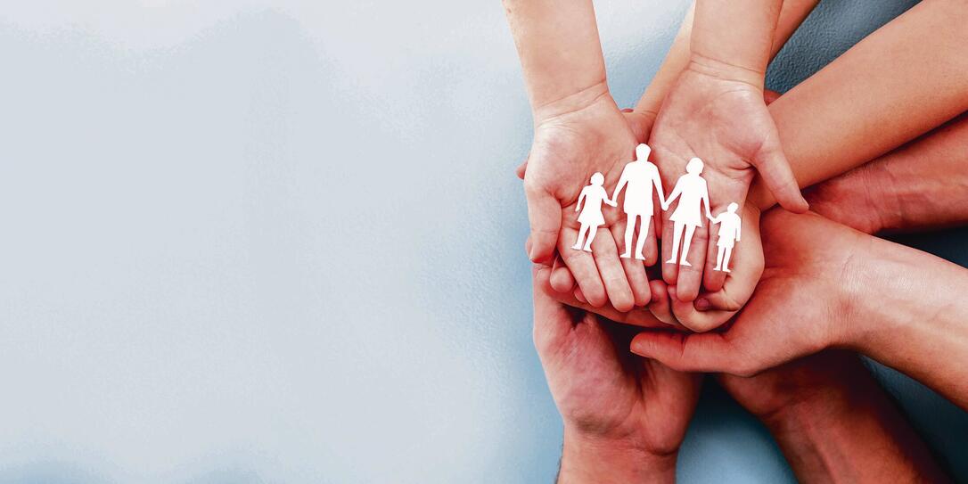 Family care concept. Hands with paper silhouette on table.