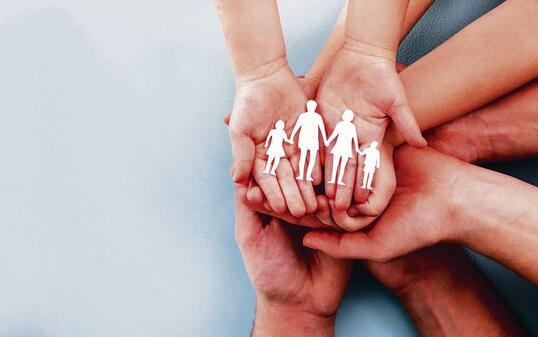 Family care concept. Hands with paper silhouette on table.