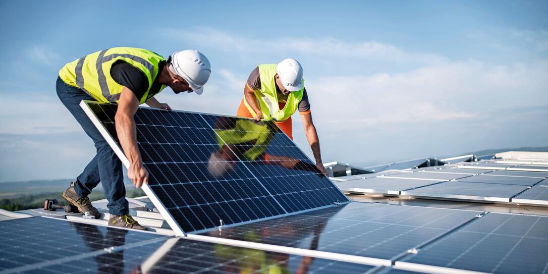 Two engineers installing solar panels on roof.