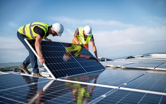 Two engineers installing solar panels on roof.