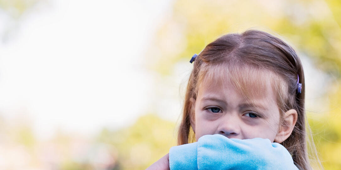 A little girl sneezing in to get elbow