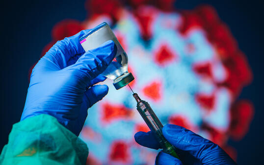 Coronavirus Covid-19 Protection and Vaccine. Doctor drawing up solution from vaccine bottle and filling syringe injection for patient vaccination in medical clinic, Coronavirus in background