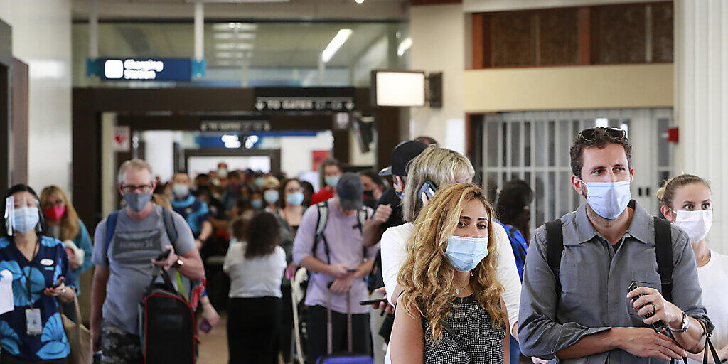 Reisende an einem Flughafen auf Hawaii tragen Mund-Nasen-Schutz. Foto: Marco Garcia/AP/dpa