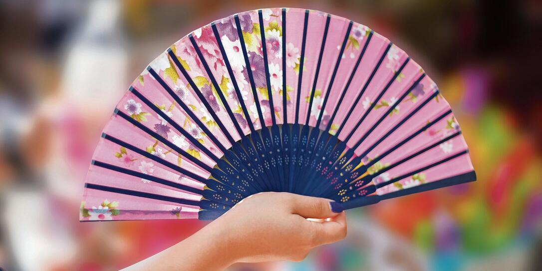 Hand holding fan on small shop blur background.