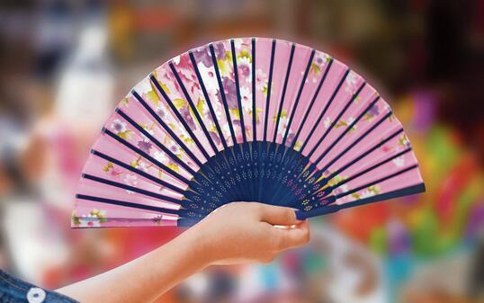 Hand holding fan on small shop blur background.