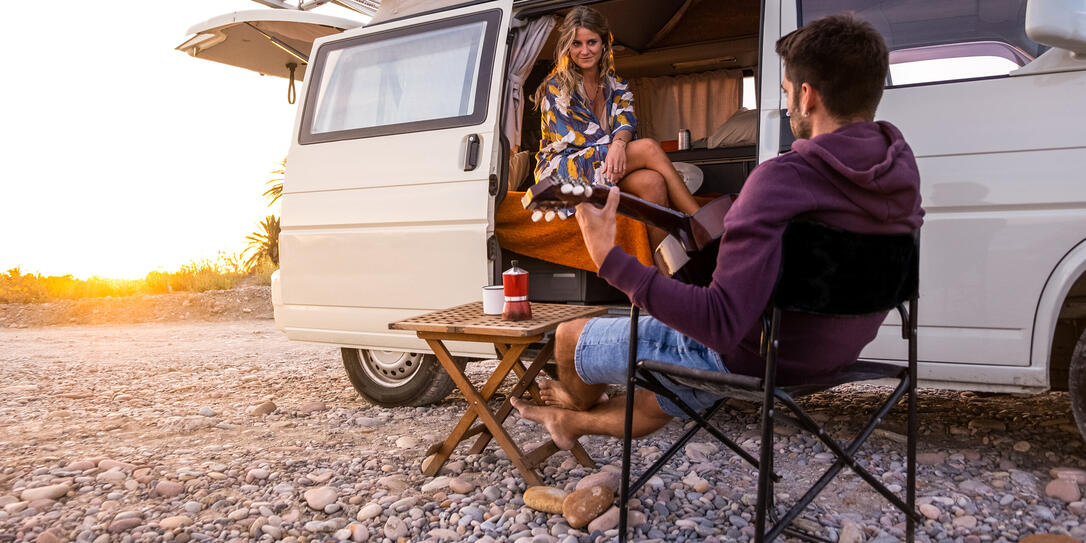 Couple with their camper van on a beach at sunset