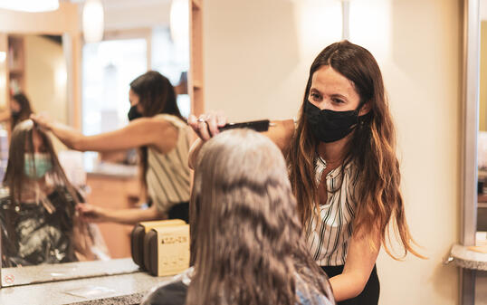 hairdresser with mask enjoying to work again in her hair salon after lockdown is over