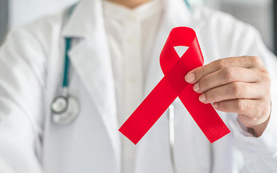 Aids red ribbon in doctor's hand for World aids day and HIV virus awareness concept