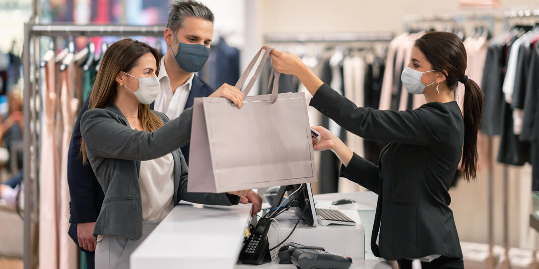 Couple shopping at a clothing store and using facemasks during the pandemic