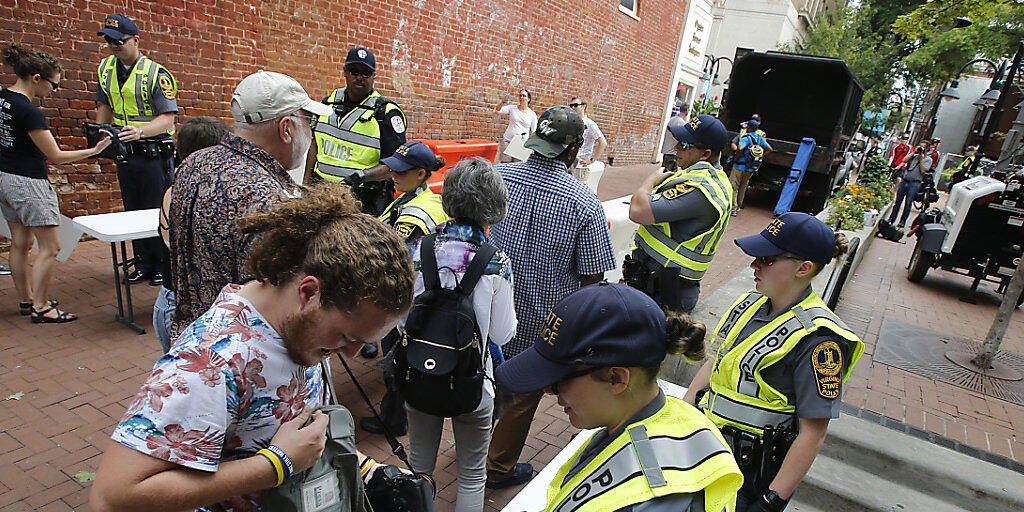 Die Polizei in Charlottesville kontrolliert Taschen. Zum Jahrestag der tödlichen Ausschreitungen an diesem Sonntag haben die Stadt Charlottesville und der Bundesstaat Virginia aus Sorge vor neuen Zwischenfällen den Notstand ausgerufen.