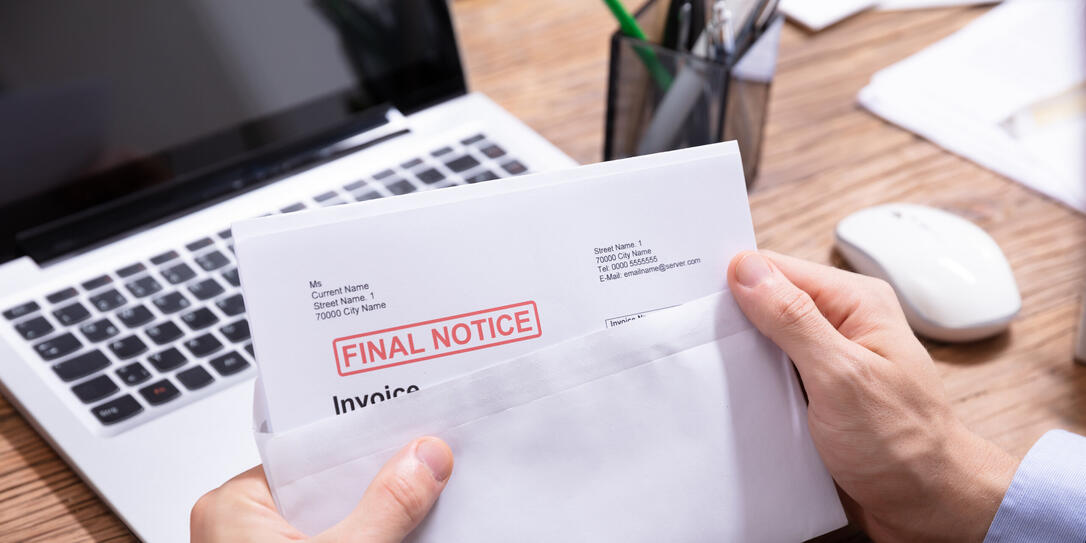 Person Holding Final Notice Invoice In Envelope
