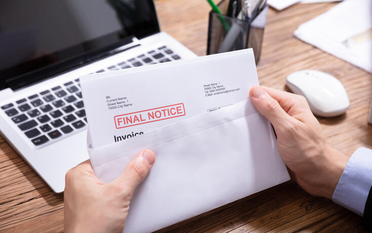 Person Holding Final Notice Invoice In Envelope