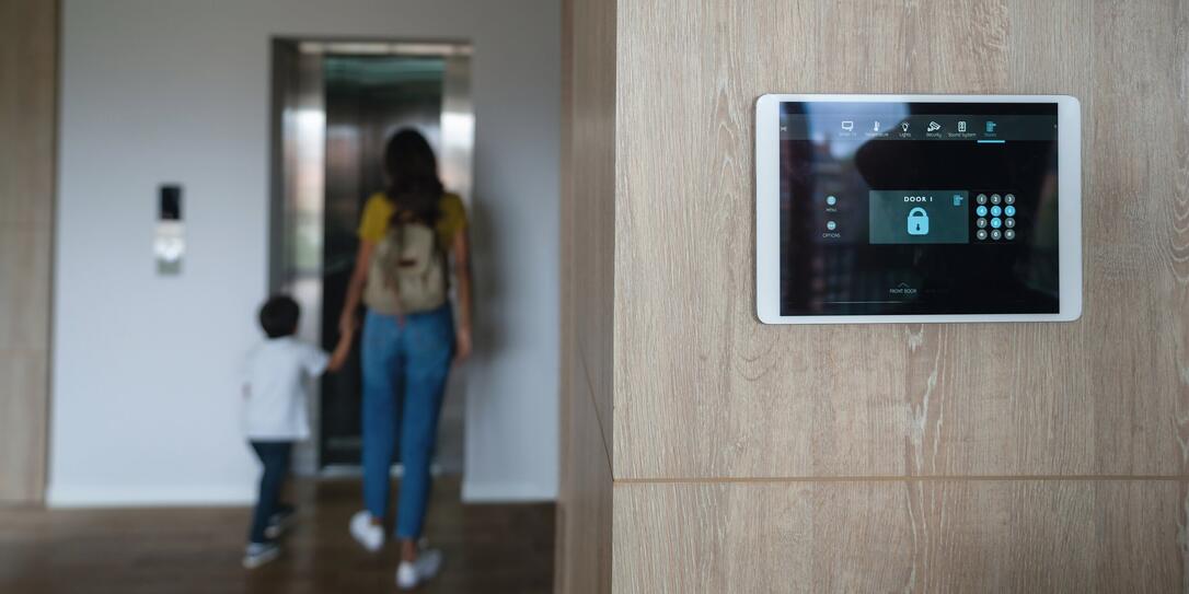 Mother and son leaving the house and locking the door using an automated security system