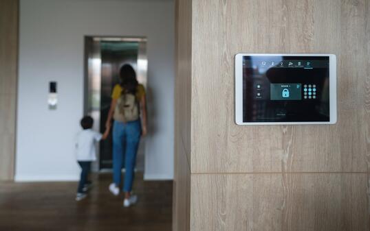 Mother and son leaving the house and locking the door using an automated security system