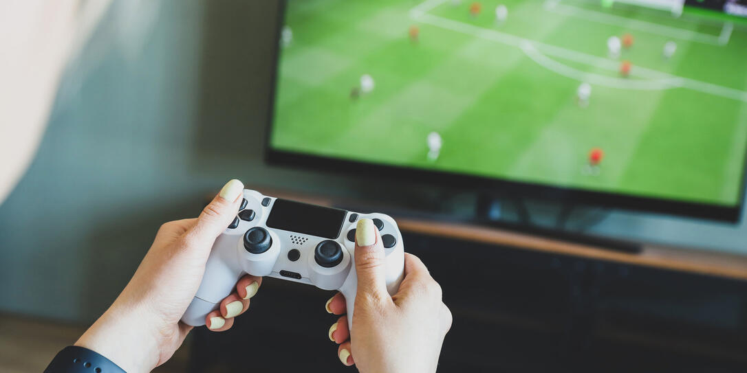 Girl playing a video game console. Game is football. Joystick in hands. Selective focus