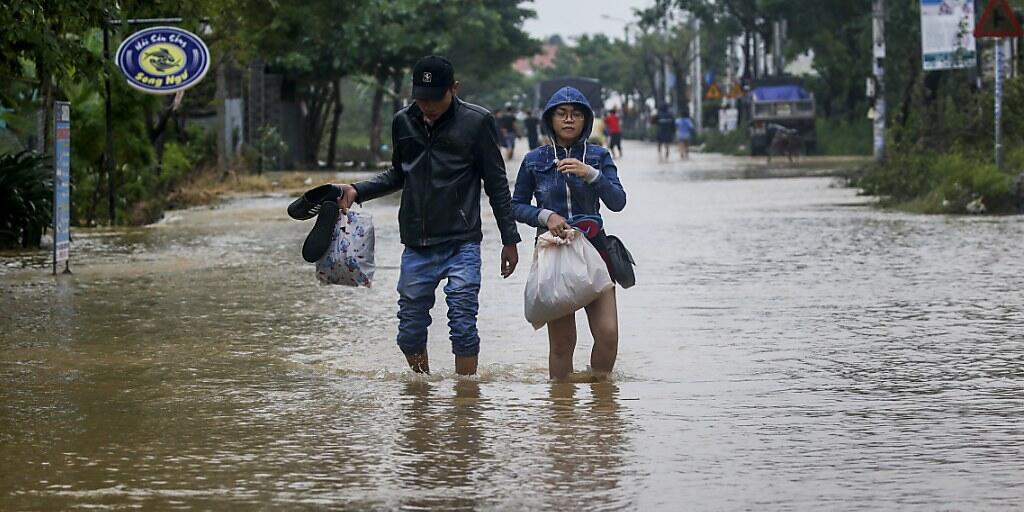 Ein Paar watet durch eine überflutete Strasse in Hoi An.