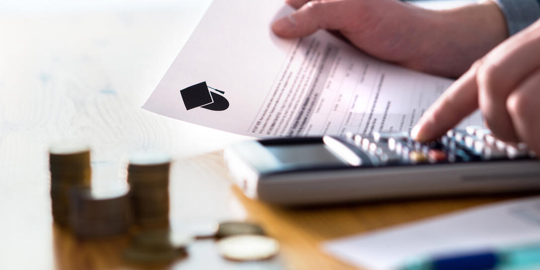 Man counting college savings fund, tuition fee or student loan with calculator. Education price and expenses concept. Money and papers on table.