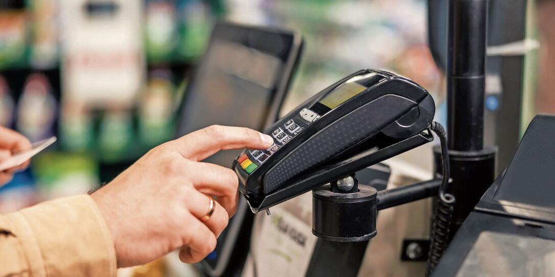 Close up of a man entering his credit card code on self-service cash out pos at supermarket.