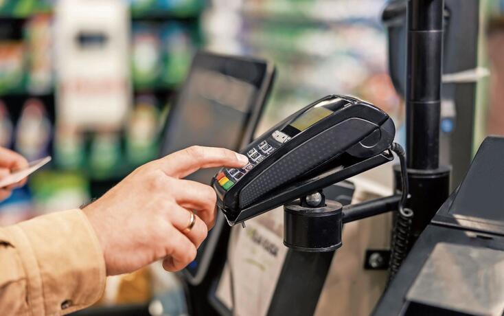 Close up of a man entering his credit card code on self-service cash out pos at supermarket.