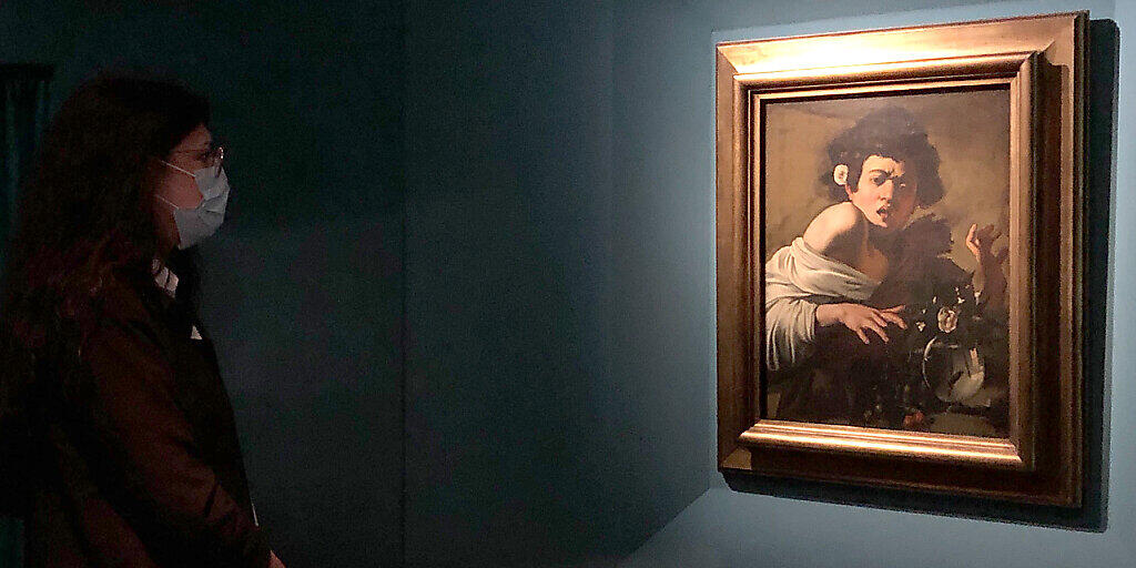Ein Frau vor dem Gemälde «Jüngling, von einer Eidechse gebissen» von Michelangelo Merisi da Caravaggio in der Sonderausstellung in den Kapitolinischen Museen. Foto: Alvise Armellini/dpa - ACHTUNG: Nur zur redaktionellen Verwendung im Zusammenhang mit einer Berichterstattung über die Ausstellung und nur mit vollständiger Nennung des vorstehenden Credits