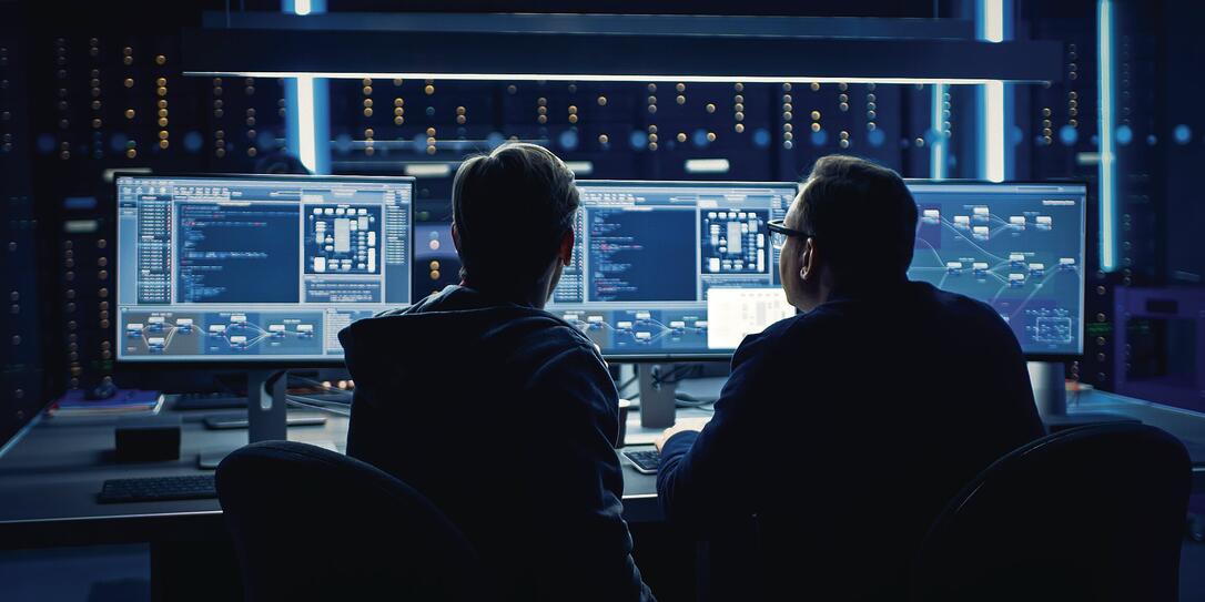 Two Professional IT Programers Discussing Blockchain Data Network Architecture Design and Development Shown on Desktop Computer Display. Working Data Center Technical Department with Server Racks