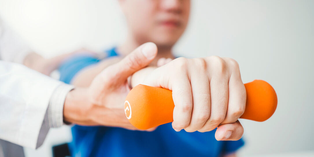 Physiotherapist man giving exercise with dumbbell treatment About Arm and Shoulder of athlete male patient Physical therapy concept