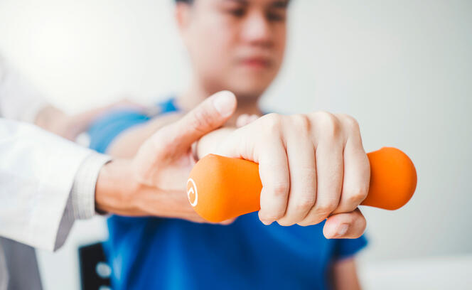 Physiotherapist man giving exercise with dumbbell treatment About Arm and Shoulder of athlete male patient Physical therapy concept