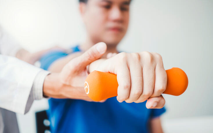 Physiotherapist man giving exercise with dumbbell treatment About Arm and Shoulder of athlete male patient Physical therapy concept