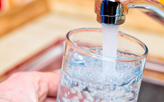 Filling up a glass with water from kitchen tap POV