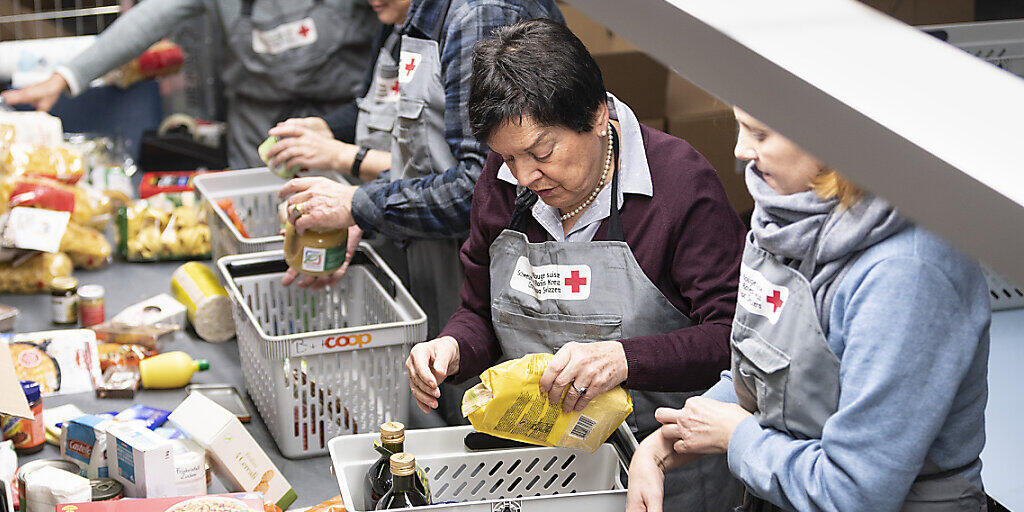 Freiwillige Helfer des Schweizerischen Roten Kreuzes kontrollieren und sortieren den Inhalt von gespendeten Paketen der Spendenaktion "2x Weihnachten". (Archivbild)