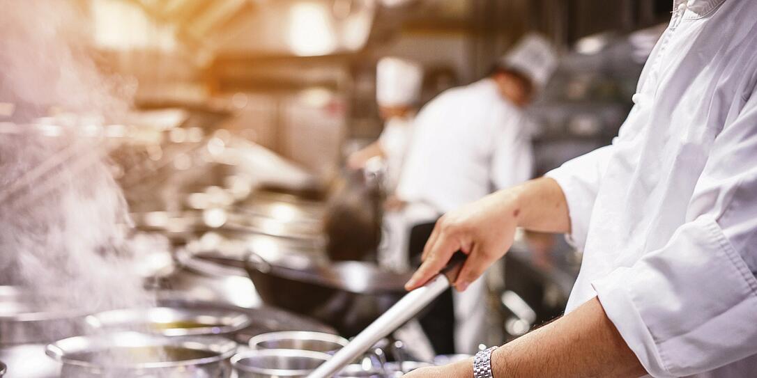 Chef in restaurant kitchen at stove with pan Chef in restaurant kitchen at stove with pan