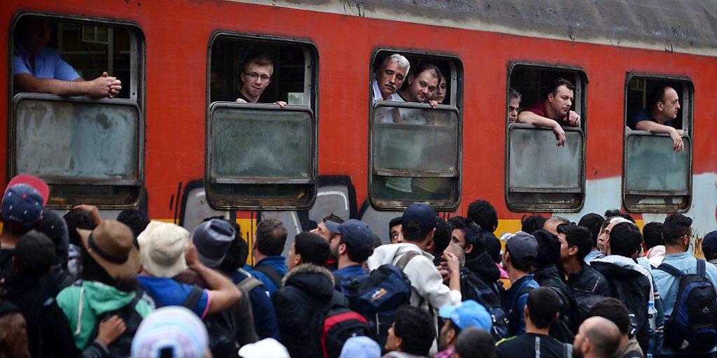 Migranten warten an einem Bahnhof in Mazedonien darauf, einen Zug Richtung Serbien zu besteigen Migranten warten an einem Bahnhof in Mazedonien darauf, einen Zug Richtung Serbien zu besteigen