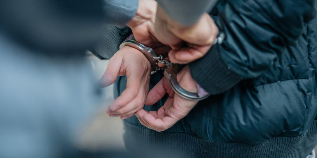 Policeman unlocking a handcuffs on the criminal's back Policeman unlocking a handcuffs on the criminal's back