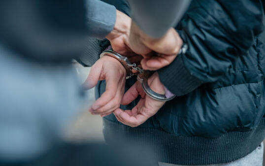 Policeman unlocking a handcuffs on the criminal's back